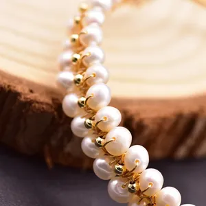 Close-up of handmade natural freshwater pearl bracelet with gold wire wrapping detail.