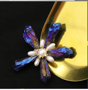 Exquisite close-up of handmade raw purple crystal and baroque pearl brooch on gold tray