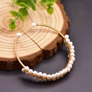 Detail showing intricate handmade gold wire wrapping with natural freshwater pearls
