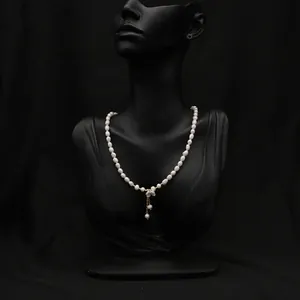 Detailed macro shot of natural pearl necklace featuring a dainty gold flower pendant
