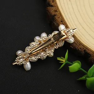 Detailed back view of vintage gold filigree pearl hair clip with spring mechanism