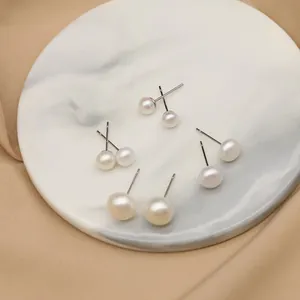 Primo piano di orecchini a perno con perle d'acqua dolce di varie dimensioni su marmo