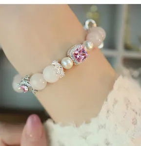 Close-up detail of a luxury pink crystal and pearl beaded elastic bracelet on a wrist.