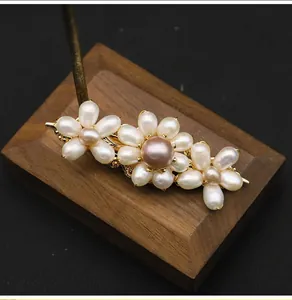 Detail view of handmade floral hair clip with natural pearls and gold hardware.