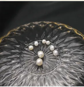 Dettaglio di diverse dimensioni di orecchini a perno con perle d'acqua dolce su vetro.