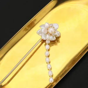Macro view of natural baroque pearl flower and elegant tassel on golden hairpin detail.