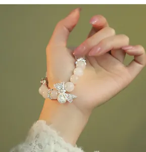 Detailed view of an elegant rose quartz beaded bracelet with a sparkling silver bow charm.