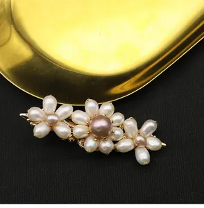 Close-up of a handmade hair clip featuring white and mauve natural pearl flowers.