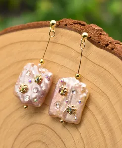 Macro view of pink baroque pearl drop earrings with rhinestones on wooden background