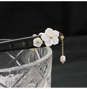 Close-up of ebony hair stick with white shell flowers and a natural pearl tassel