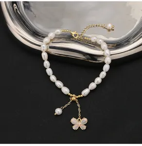 Dettaglio di bracciale con perle d'acqua dolce, ciondolo a farfalla e perline d'oro