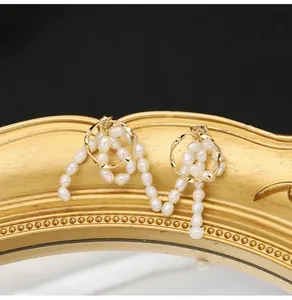 Detailansicht eleganter goldfarbener Ohrringe mit natürlichen weißen Barockperlen
