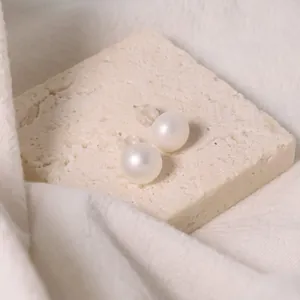 Eleganti orecchini a perno con perle d'acqua dolce bianche su sfondo in pietra grezza