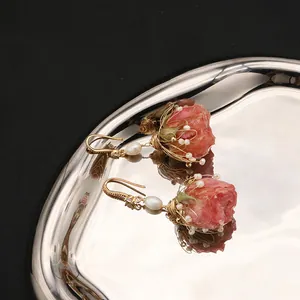 Dettaglio squisito di orecchini fatti a mano con rose e perle naturali eleganti.