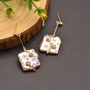 Close-up detail of baroque flat pearl earrings with crystals and gold floral accents