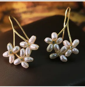 Close-up of elegant gold flower earrings with natural freshwater pearls and crystals