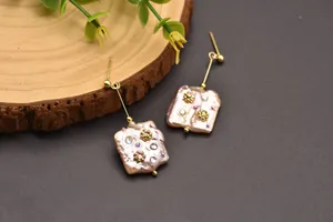 Detailed view of baroque pearl drop earrings featuring delicate crystal flower inlays.