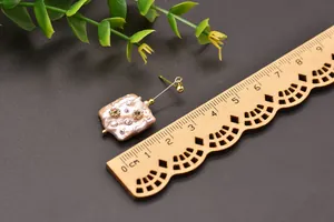Detailed view of a pink baroque pearl earring shown next to a wooden ruler for scale