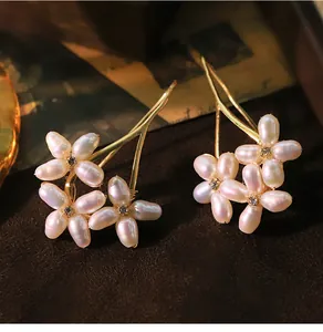 Detailed macro view of baroque natural freshwater pearl flower earrings with gold accents
