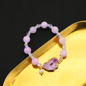 Naturperlenarmband mit lilafarbener Amethystdruse auf einem goldenen Schmucktablett