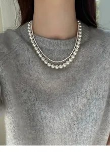 Close-up of elegant double layered pearl necklace worn with a soft grey knit sweater