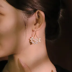 Elegant gold branch hook earrings featuring natural freshwater pearl flowers on Asian model