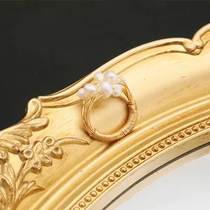 Detailansicht eines goldumwickelten Rings mit Süßwasserperlen auf einem Vintage-Rahmen.