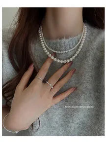 Detailed view of layered white pearl necklace set featuring 4mm and 8mm sizes on model