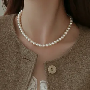 Elegant round white pearl necklace for women displayed on a model wearing a brown jacket