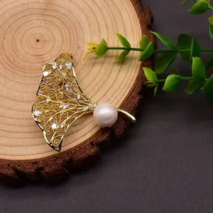 Elegante ginkgobladbroche met natuurlijke zoetwaterparel en sprankelende edelstenen. (85 chars)