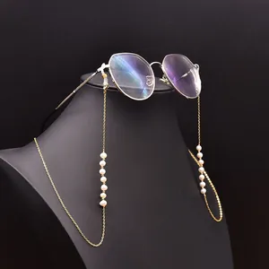 Vue détaillée d'une chaîne de lunettes dorée faite main avec des perles d'eau douce.