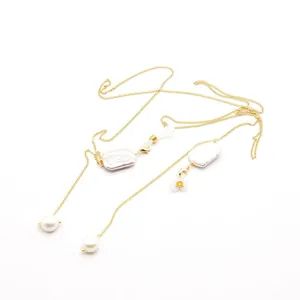 Close-up detail of a gold chain featuring natural baroque and round white pearls