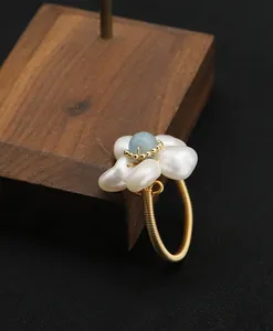 Close-up of a handmade wire-wrapped ring with natural pearls and aquamarine flower