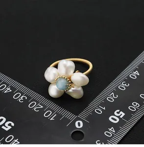 Detailed view of handmade pearl flower ring with aquamarine stone and measuring scale