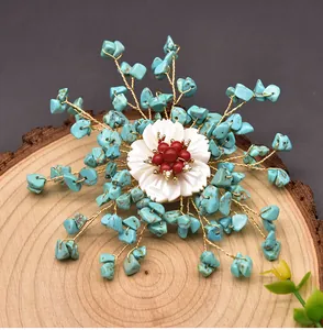 Detailansicht einer handgefertigten ethnischen Brosche mit künstlichem Türkis und Muschelblume