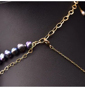 Close-up of golden multi-layer necklace with dark baroque pearls and heart-shaped links