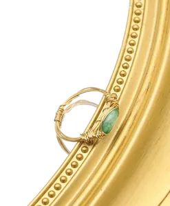Detail of handmade wire-wrapped gold ring featuring a polished green jade stone.