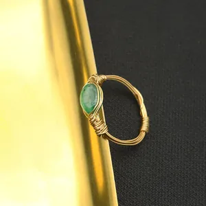 Close-up of handmade wire-wrapped ring with green jade stone and golden texture