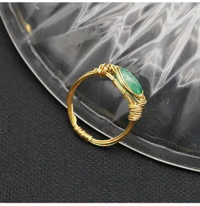 Close-up detail of handmade gold wire-wrapped ring featuring an oval green jade stone