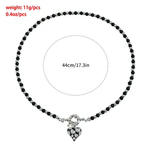 Detailed macro shot of two-tone beaded necklace featuring a sparkling rhinestone heart pendant
