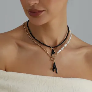 Gros plan sur un collier double rang avec perles noires, perles blanches et fermoir doré