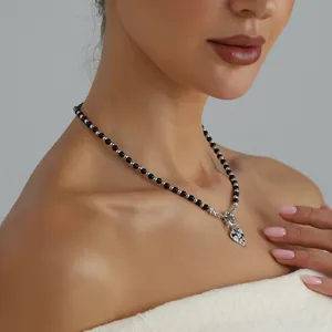 Detailed shot of beaded heart necklace worn by a female model in soft studio light