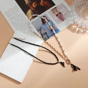 Gros plan d'un collier en perles et chaîne dorée avec pendentif plissé noir