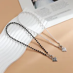 Detail of stylish beaded heart necklaces in black and white with rhinestone pendants.