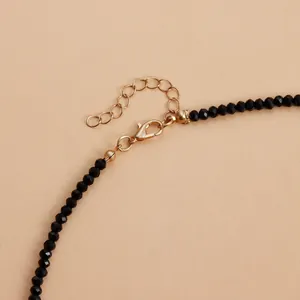 Gros plan détaillé d'un collier de perles noires facettées avec fermoir mousqueton doré.