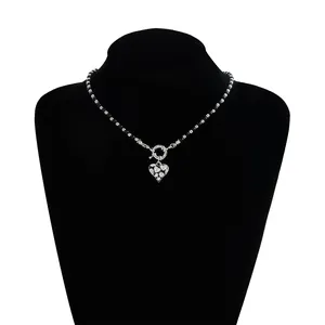 Close-up of heart-shaped pendant necklace with black beads and rhinestone detail