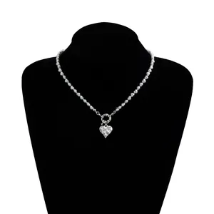 Close-up of silver beaded necklace with rhinestone heart pendant and spring ring clasp