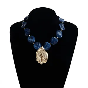 Detail einer Vintage-Halskette mit blauen Harzperlen und geprägtem Blattanhänger in Gold