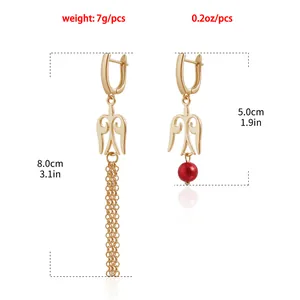 Asymmetrische goldene Hohlflügelohrringe mit langer Quaste und rotem Perlendetail