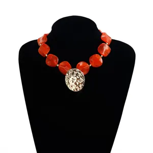 Detailansicht einer vintage orangefarbenen Harzperlenkette mit gehimmeltem Goldanhänger.